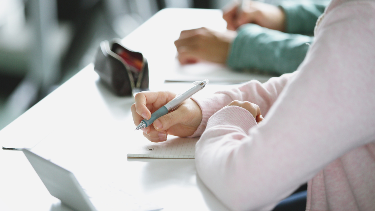 Persona escribiendo a mano en un cuaderno